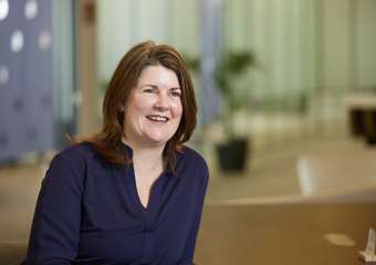 woman with brown hair sitting down and smiling