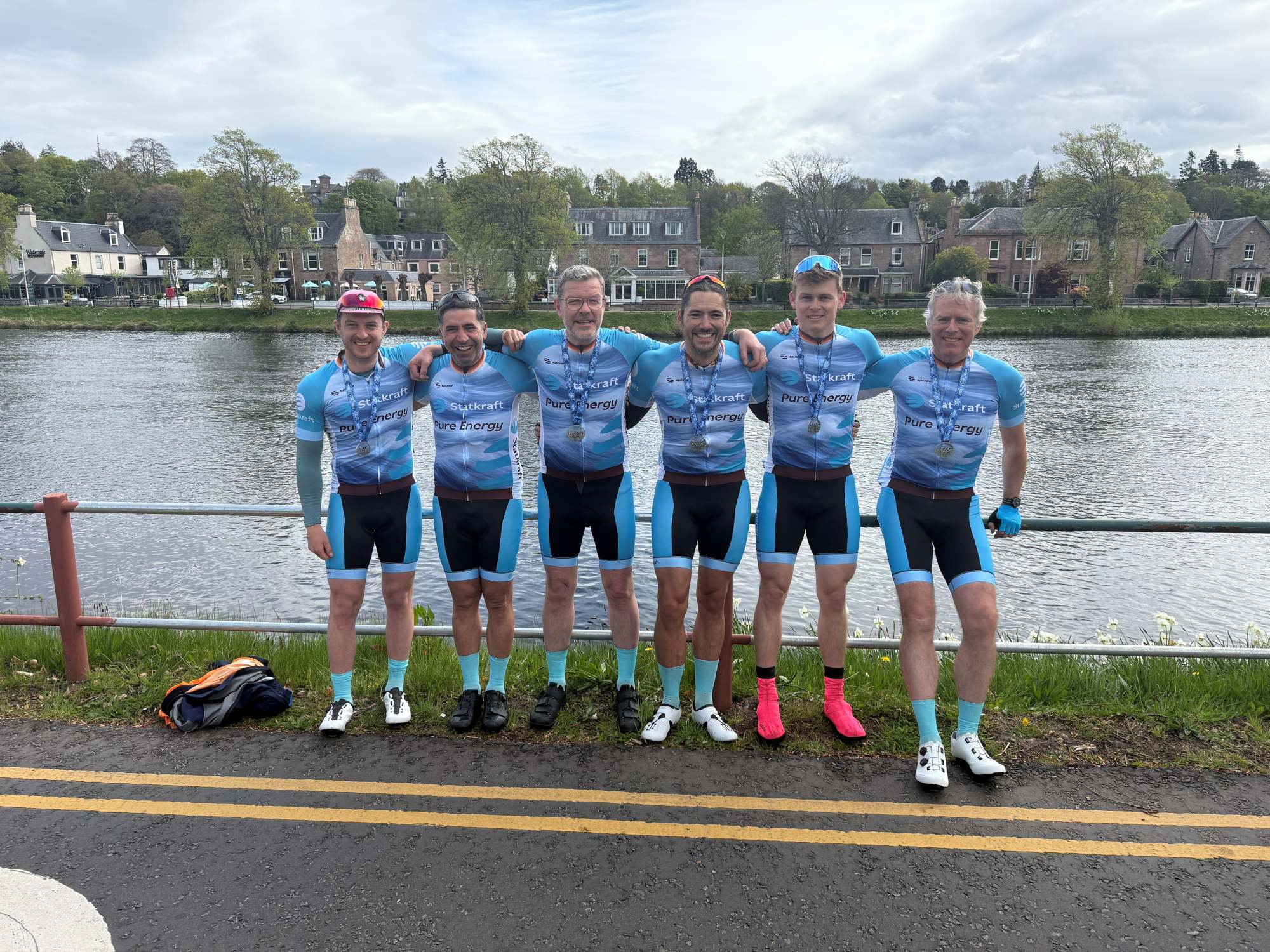 Group photo of the Statkraft Etape team, featuring Tim McKellar, Haydar Gokmen, Iain Robertson, Andrew Monin, Harry Venables, and Simon Godfrey, standing together outdoors.